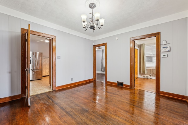 spare room featuring dark wood-style floors, baseboards, visible vents, and a notable chandelier