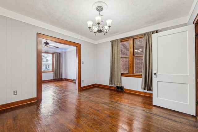 empty room with a textured ceiling, dark wood-style flooring, and a notable chandelier