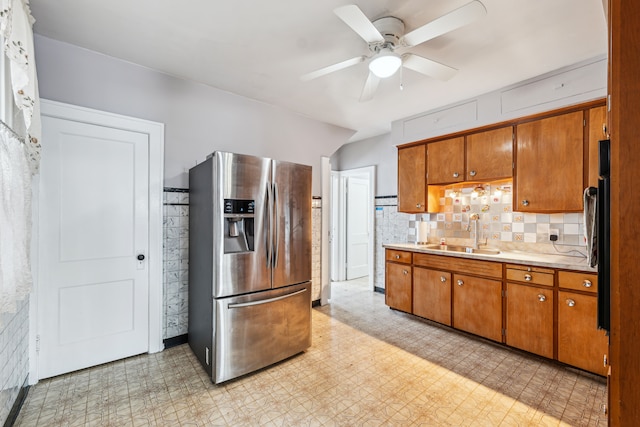 kitchen with brown cabinets, light countertops, light floors, stainless steel refrigerator with ice dispenser, and a sink