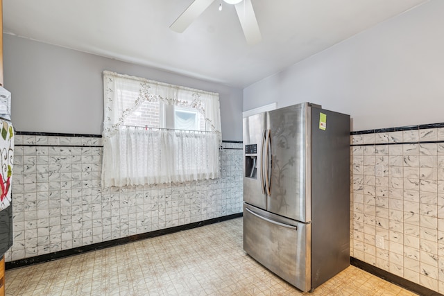 kitchen with a wainscoted wall, light floors, tile walls, and stainless steel fridge with ice dispenser