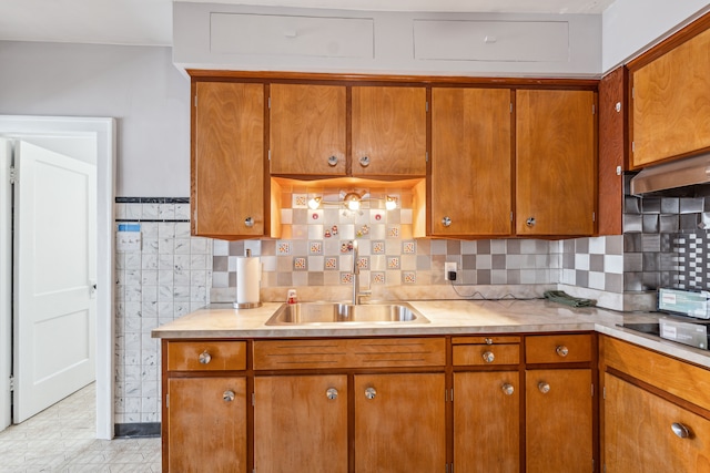 kitchen with brown cabinetry, custom exhaust hood, light countertops, and a sink