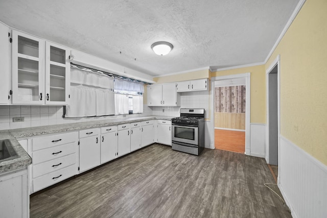 kitchen featuring dark hardwood / wood-style floors, backsplash, gas range, ornamental molding, and white cabinets