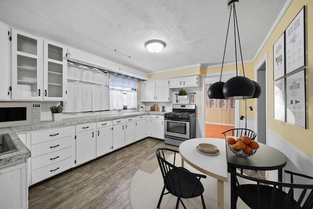 kitchen featuring white cabinetry, decorative backsplash, decorative light fixtures, gas range, and crown molding