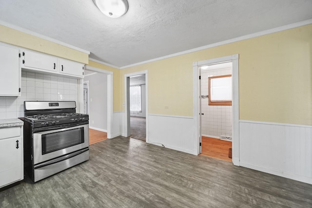 kitchen featuring dark wood-type flooring, stainless steel gas range, white cabinetry, and ornamental molding