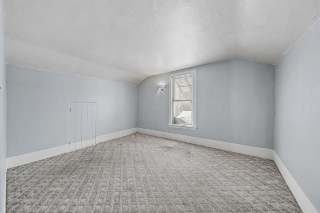 additional living space with a textured ceiling, carpet flooring, and lofted ceiling