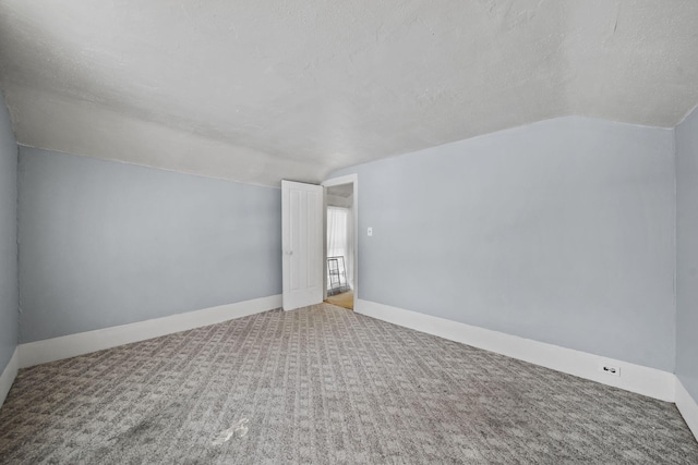 carpeted empty room with a textured ceiling and lofted ceiling