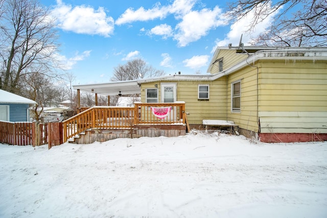 snow covered rear of property with a wooden deck