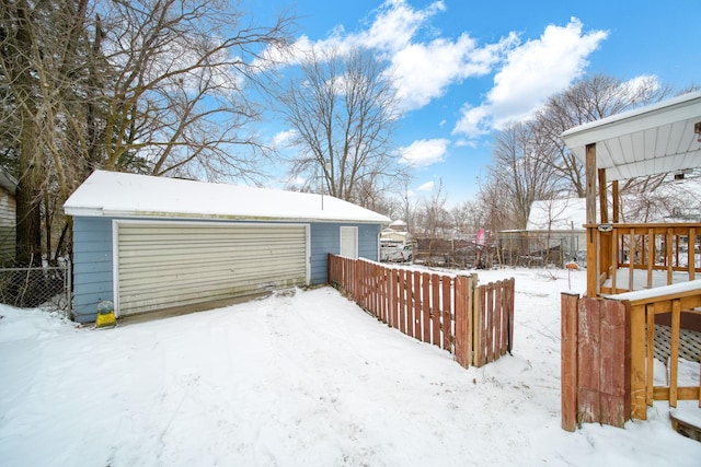 snowy yard featuring a garage and an outbuilding