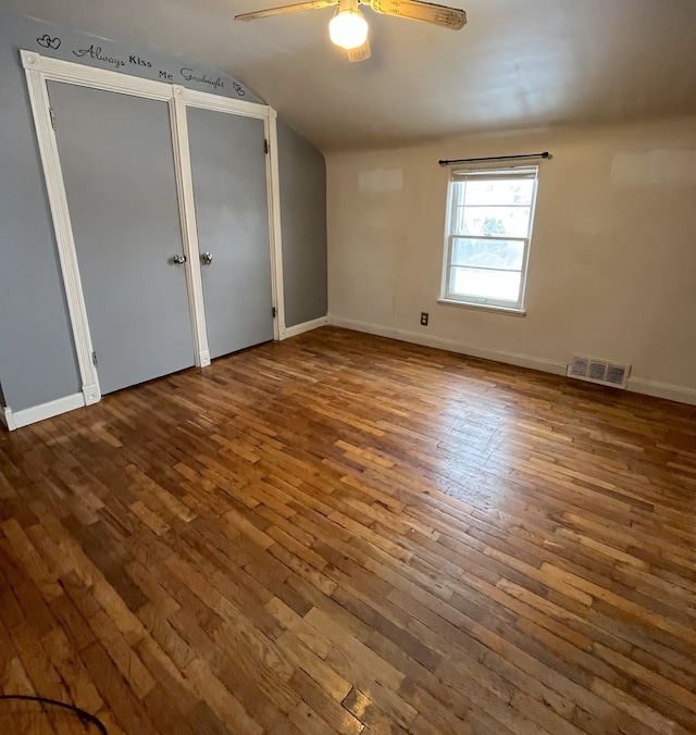 unfurnished bedroom with ceiling fan, lofted ceiling, hardwood / wood-style flooring, and multiple closets