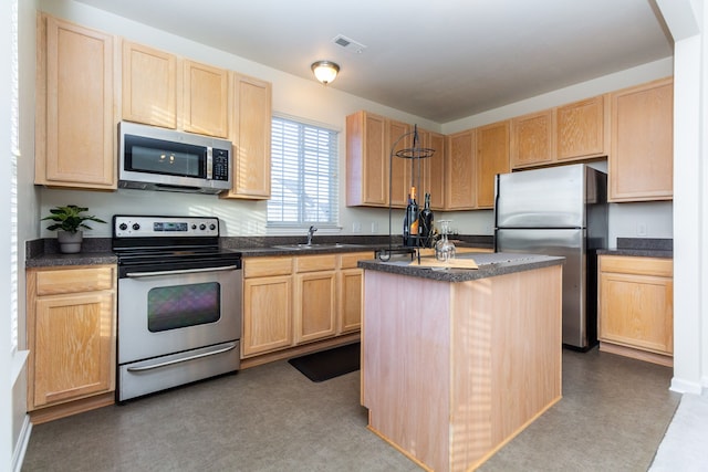 kitchen with appliances with stainless steel finishes, light brown cabinets, a kitchen island, and sink