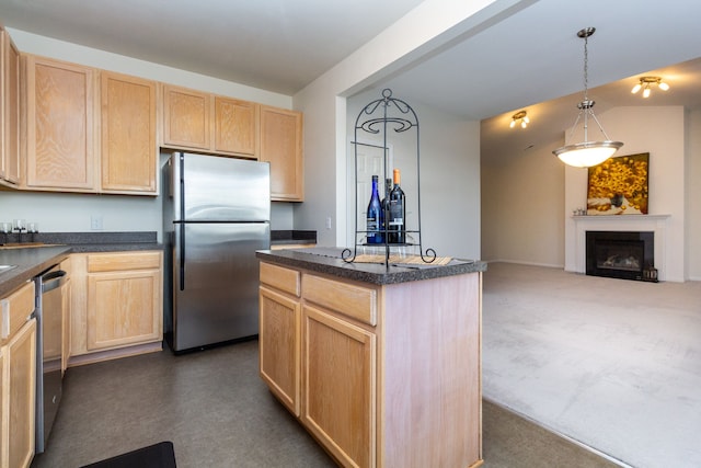 kitchen with appliances with stainless steel finishes, pendant lighting, light brown cabinets, and a kitchen island