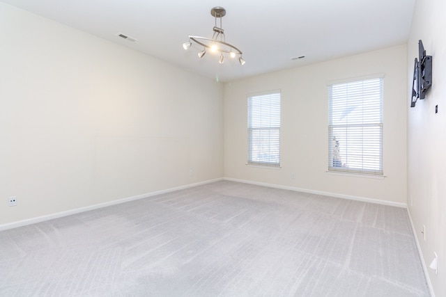 carpeted empty room with a chandelier