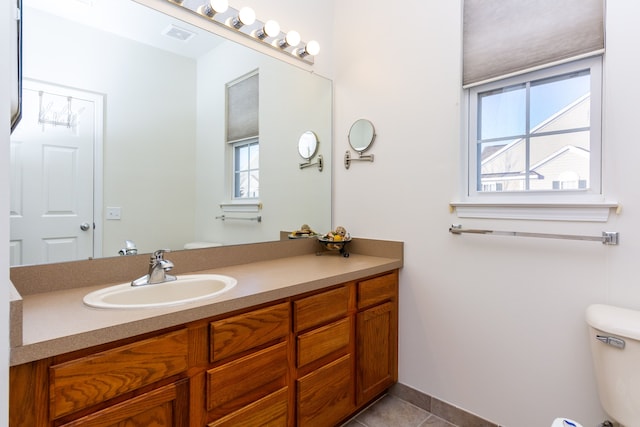 bathroom with toilet, vanity, and tile patterned flooring