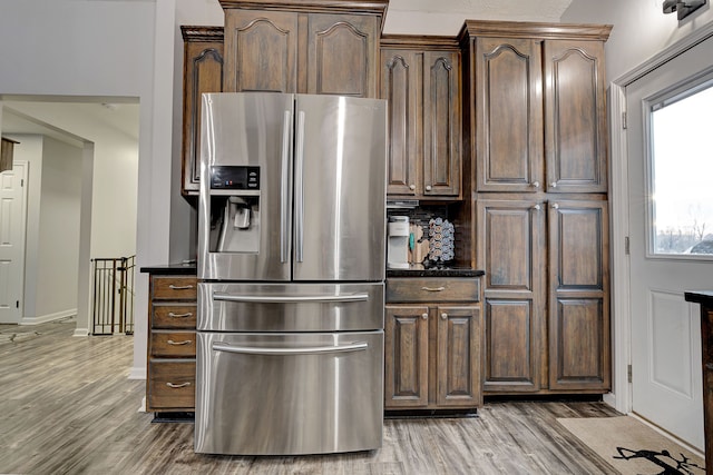 kitchen with stainless steel fridge with ice dispenser, backsplash, wood-type flooring, and dark brown cabinets