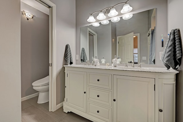 bathroom with toilet, vanity, and tile patterned flooring