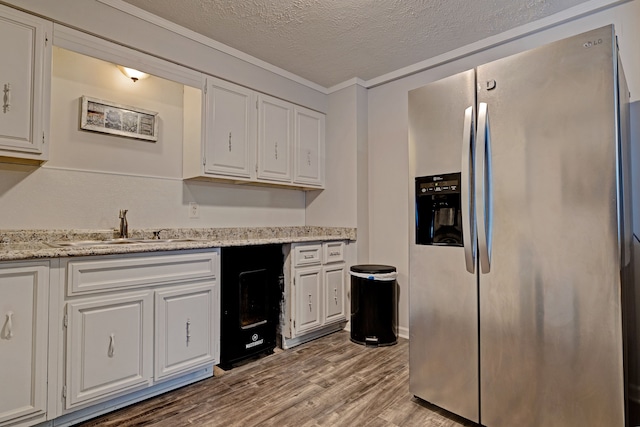 kitchen featuring light wood-type flooring, white cabinetry, stainless steel fridge, and sink