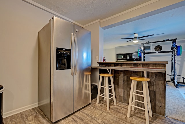 kitchen featuring a breakfast bar, stainless steel fridge with ice dispenser, a textured ceiling, and hardwood / wood-style floors