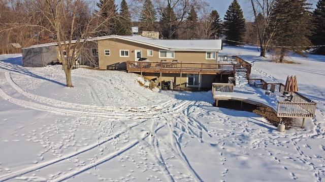 snow covered rear of property with a wooden deck