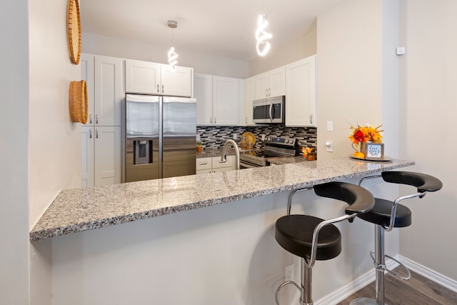 kitchen featuring kitchen peninsula, appliances with stainless steel finishes, and white cabinetry