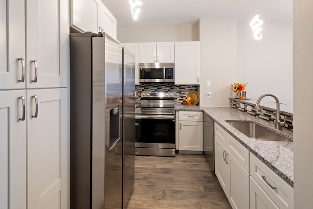 kitchen with hanging light fixtures, white cabinets, sink, and stainless steel appliances