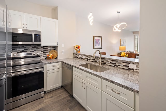 kitchen with white cabinets, decorative light fixtures, stainless steel appliances, sink, and backsplash