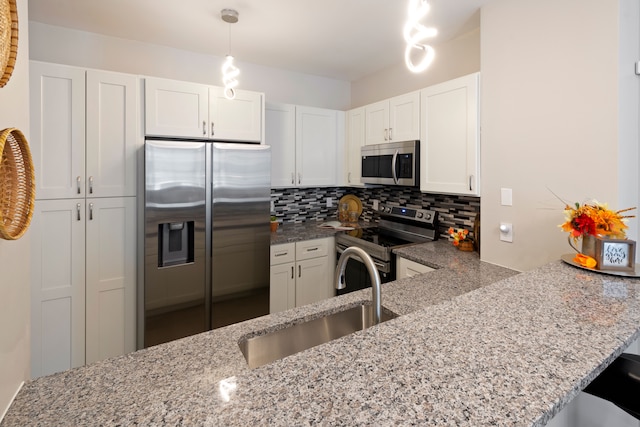 kitchen featuring kitchen peninsula, appliances with stainless steel finishes, sink, and white cabinetry