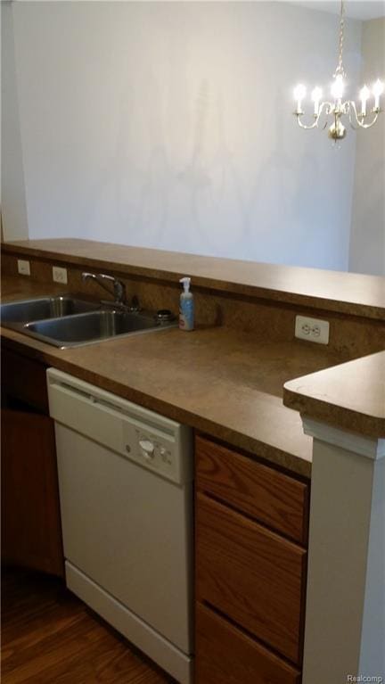 kitchen featuring a notable chandelier, pendant lighting, sink, white dishwasher, and dark wood-type flooring