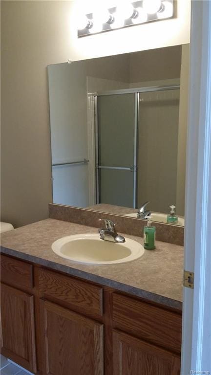 bathroom featuring an enclosed shower, vanity, tile patterned floors, and toilet