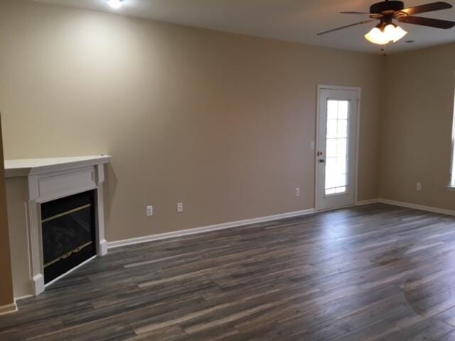 unfurnished living room with ceiling fan, dark hardwood / wood-style floors, and a wealth of natural light