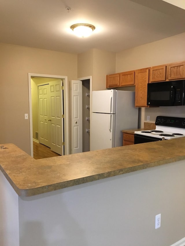 kitchen featuring range with electric stovetop, kitchen peninsula, and white refrigerator