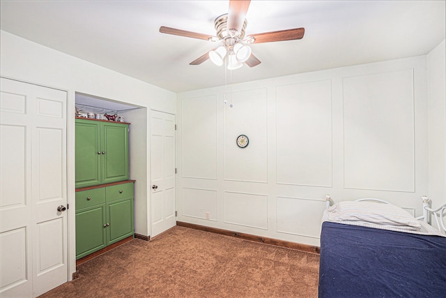 unfurnished bedroom with ceiling fan and dark carpet