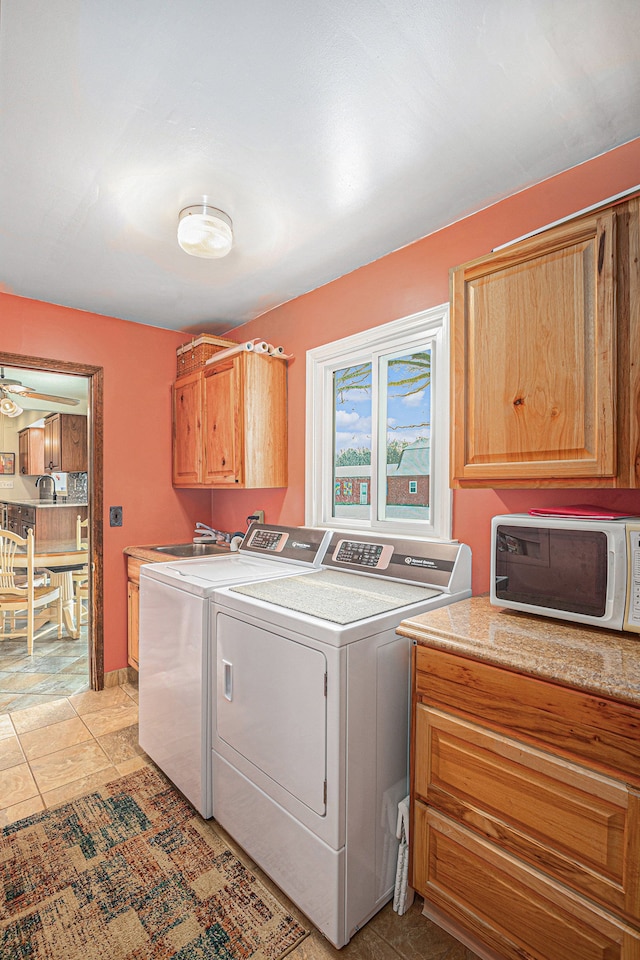 laundry room featuring washer and dryer, cabinets, and light tile patterned floors