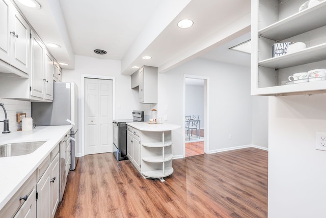 kitchen featuring tasteful backsplash, white cabinets, stainless steel electric range, light hardwood / wood-style flooring, and sink