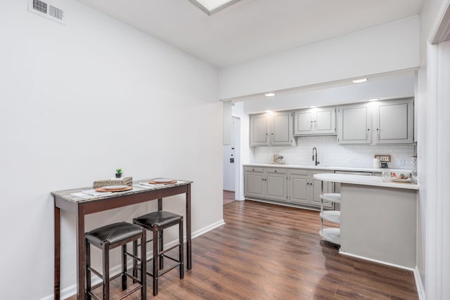 kitchen with backsplash, sink, gray cabinetry, and a breakfast bar area