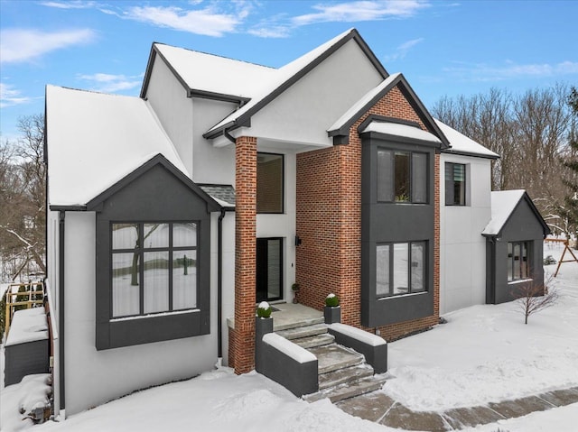 view of front of home featuring brick siding and stucco siding