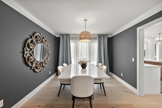 dining space featuring baseboards, light wood-style flooring, and crown molding