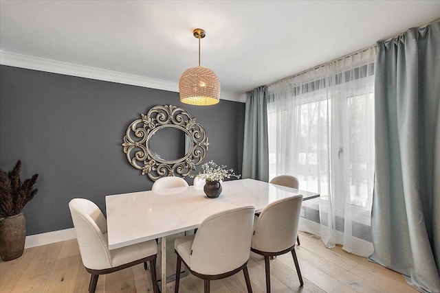 dining area with light wood-style flooring, baseboards, and crown molding