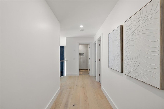 corridor featuring light wood-type flooring and baseboards