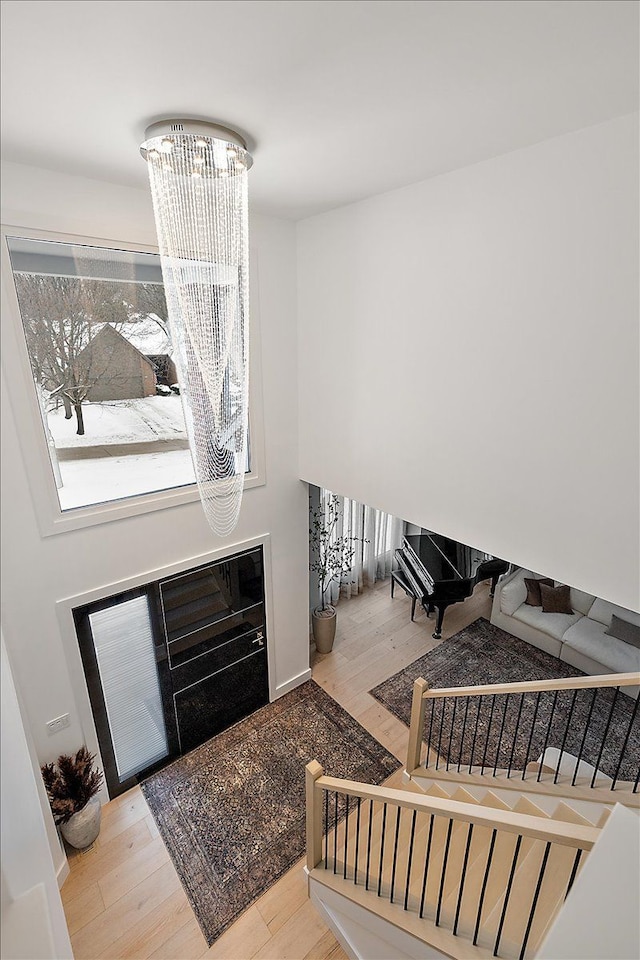 foyer featuring light wood-type flooring, an inviting chandelier, and stairs