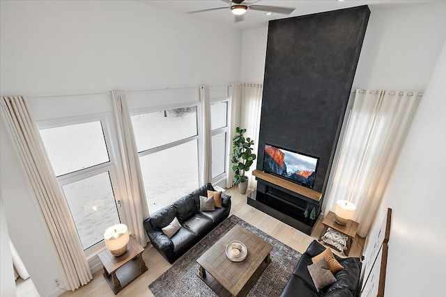 living room with light wood-style floors, ceiling fan, and a multi sided fireplace