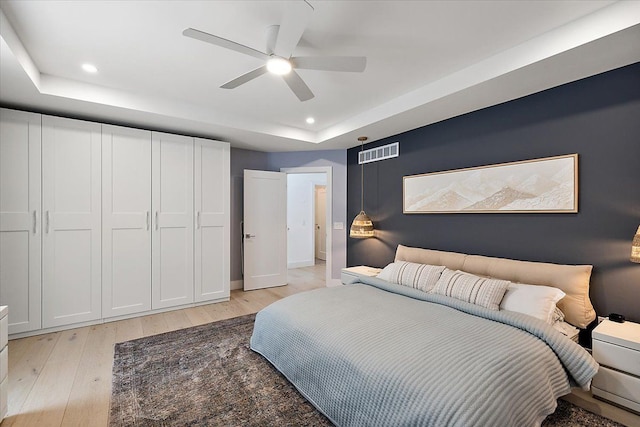 bedroom featuring visible vents, a ceiling fan, light wood-style flooring, a tray ceiling, and recessed lighting