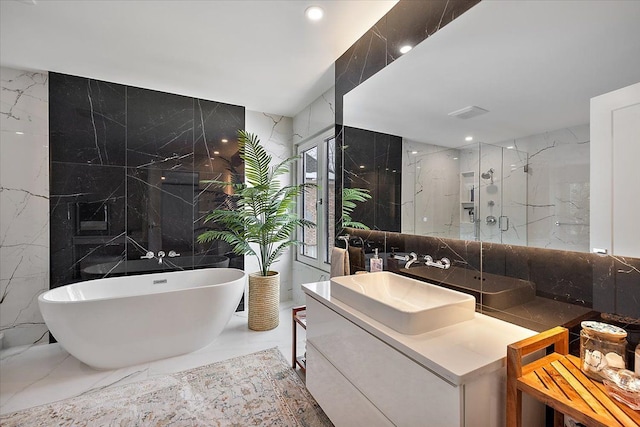 bathroom featuring marble finish floor, tile walls, a marble finish shower, a freestanding tub, and stone wall