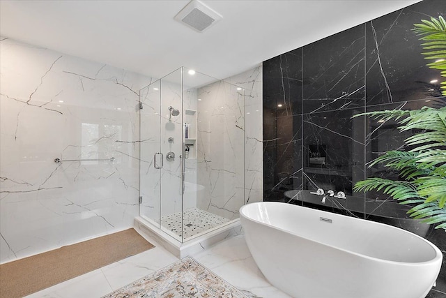 bathroom featuring marble finish floor, a marble finish shower, visible vents, a freestanding tub, and stone wall