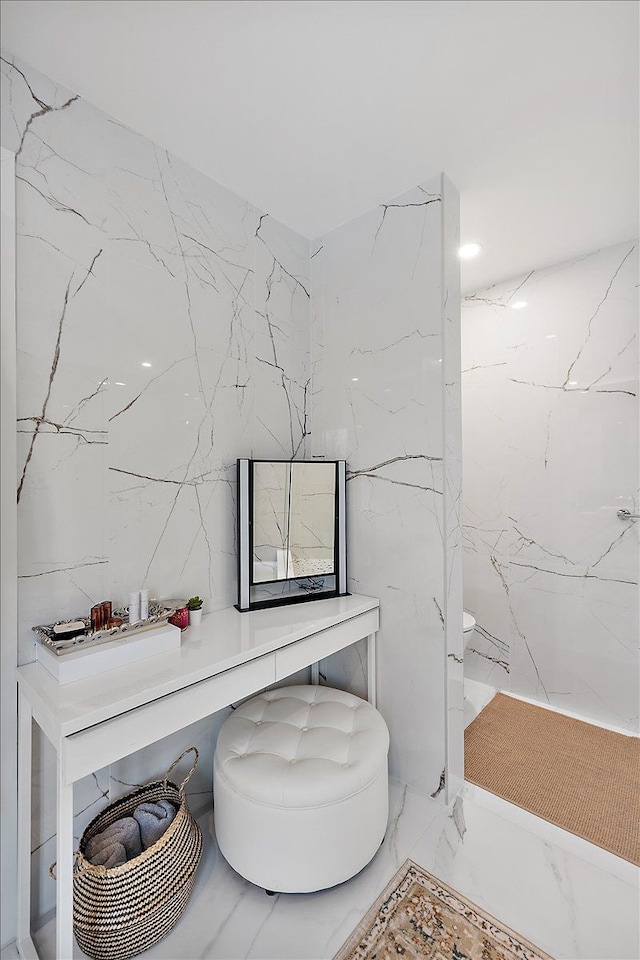 bathroom with marble finish floor, stone wall, and tile walls