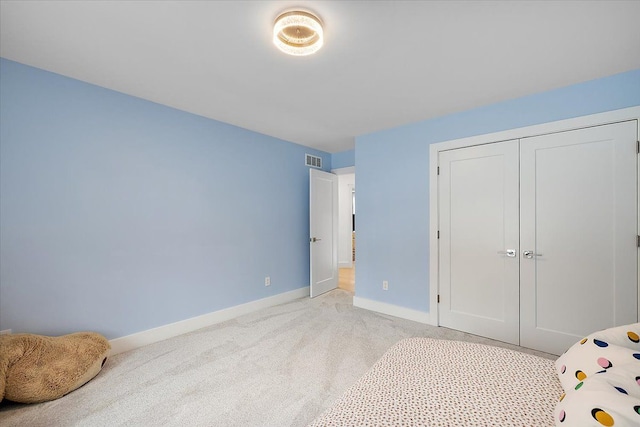 bedroom featuring baseboards, a closet, visible vents, and light colored carpet