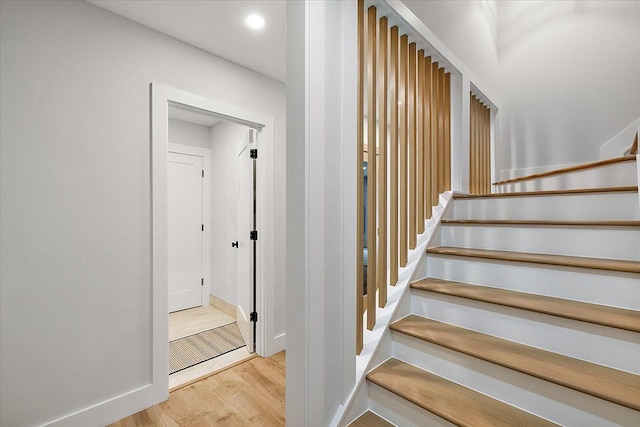 stairs with baseboards, wood finished floors, and recessed lighting