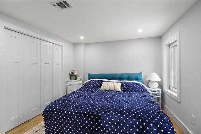 bedroom with recessed lighting, a closet, visible vents, wood finished floors, and baseboards