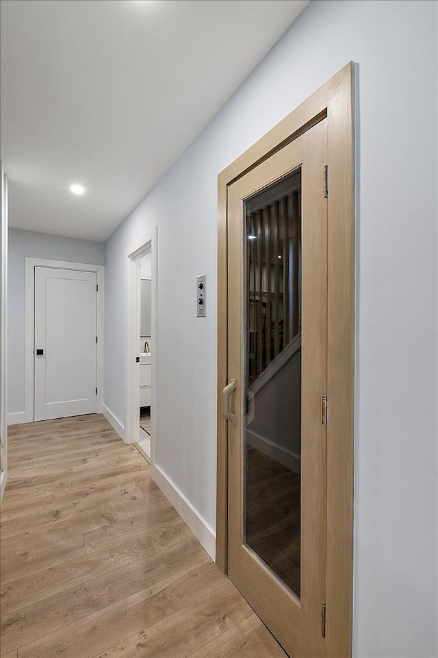 hall featuring baseboards, a sauna, and light wood-style floors