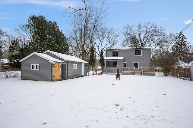 snow covered rear of property with a wooden deck