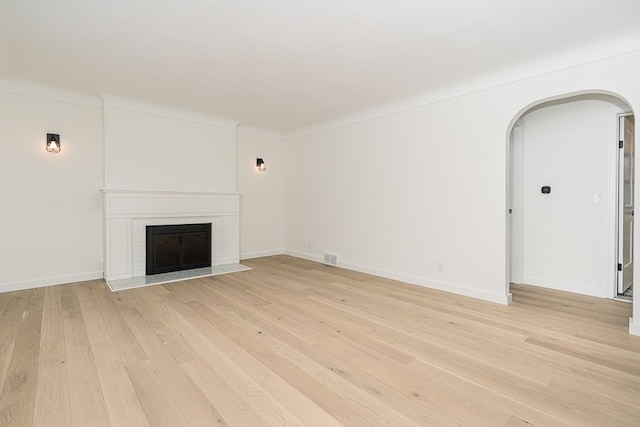 unfurnished living room featuring crown molding and light wood-type flooring